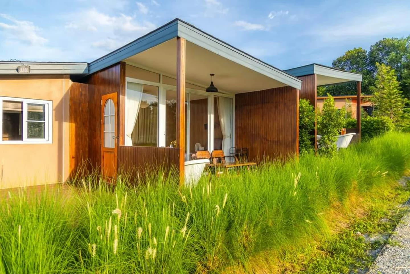 Casa de una planta con revestimiento de madera y jardín abierto.