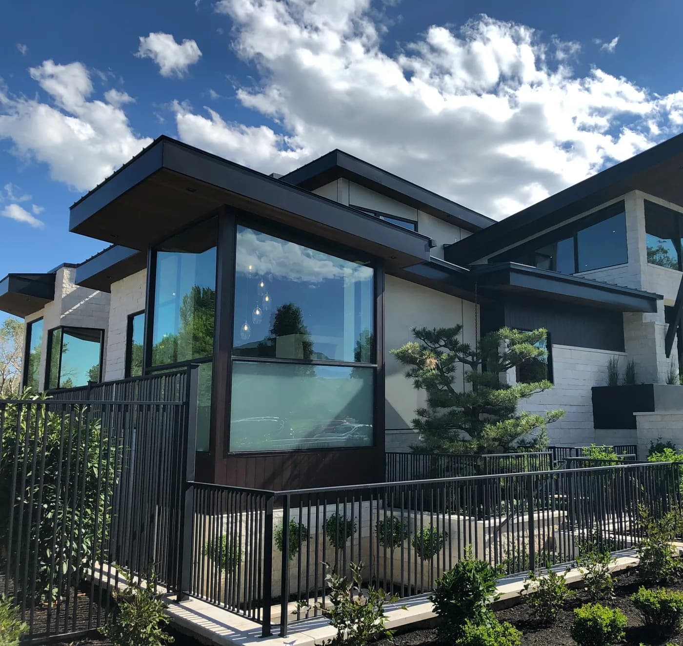Vivienda contemporánea con ventanales, muros de piedra clara y jardín.